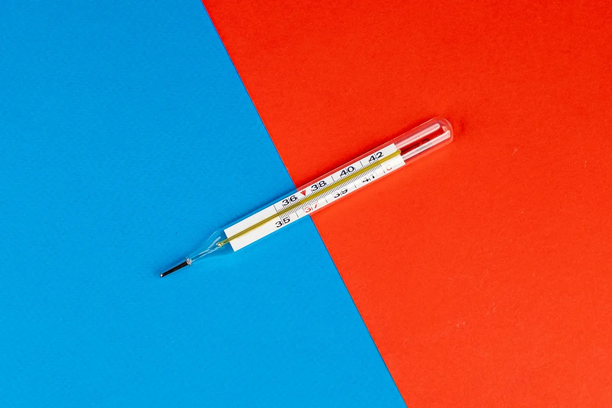 Chambre fermée en pleine chaleur avec thermomètre affichant une température élevée sur la table de nuit