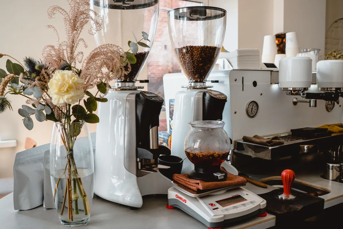 Grains de café entiers à côté d'un moulin et d'une cafetière, prêts à la préparation