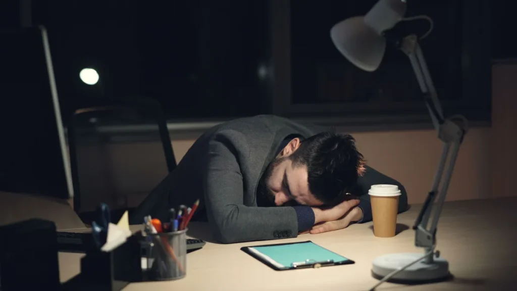 Personne assise à son bureau prenant une pause consciente, mains reposées, lumière naturelle.