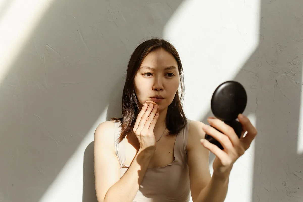 Femme appliquant un soin solaire dans sa routine beauté estivale