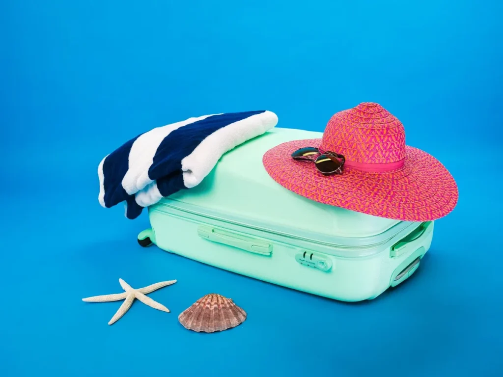Produits de beauté d'été disposés dans une pochette de plage ouverte sur le sable