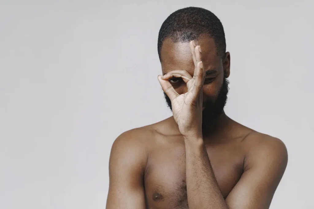 Personne se touchant le visage avec une expression préoccupée dans un environnement neutre
