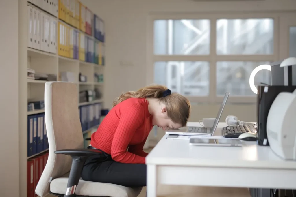 Personne fatiguée à son bureau le matin après une nuit blanche, lumière naturelle douce