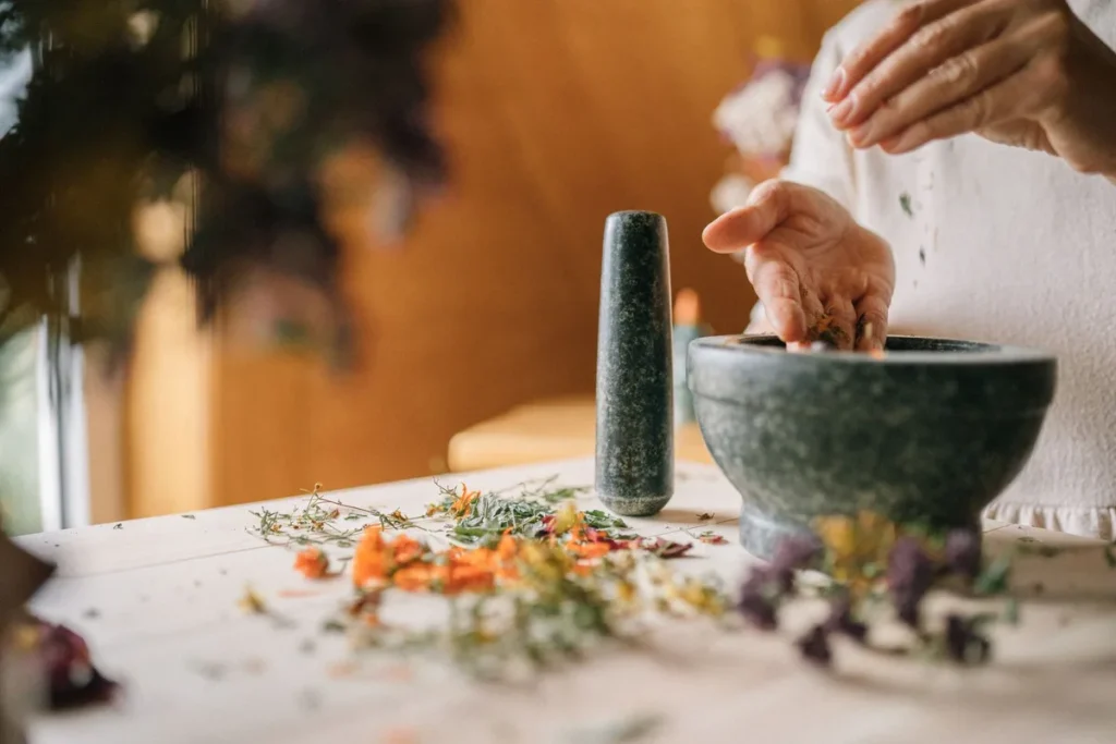 Mains versant un liquide clair dans des bouteilles en verre avec des plantes séchées mesurées