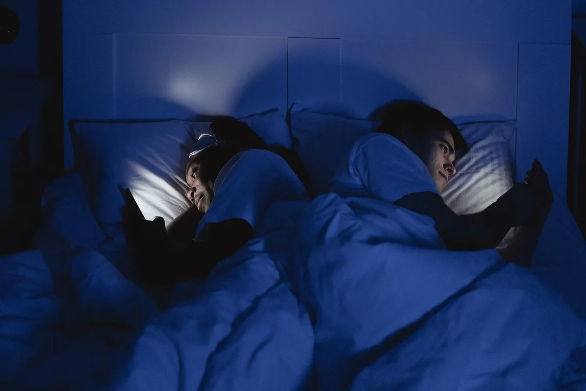 Écran de téléphone émettant une lumière bleue le soir dans un environnement sombre.