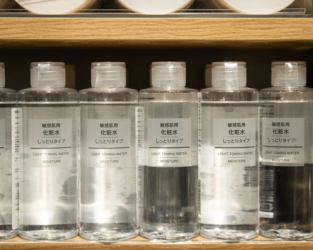 Flacons de cosmétiques (parfum, rétinol, gommage) sur une étagère de salle de bain