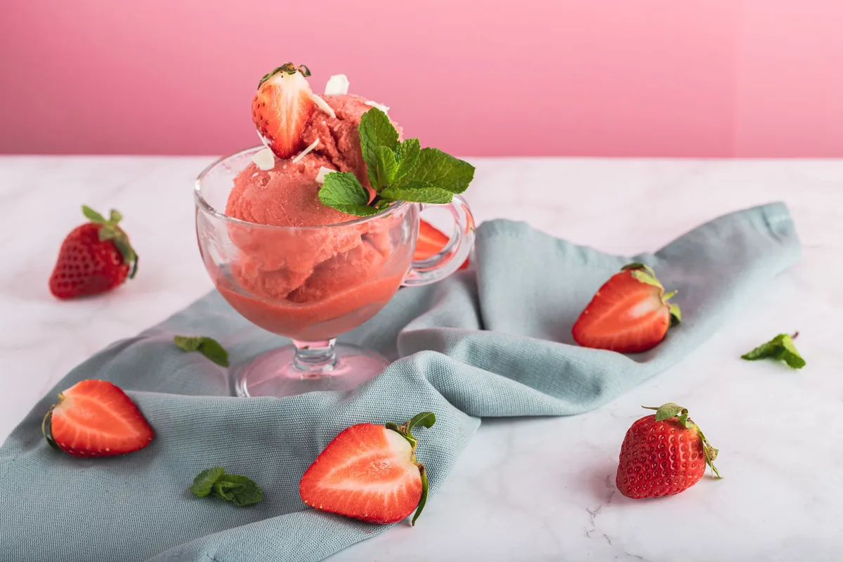 Ingrédients pour le sorbet : fraises congelées, infusion à la rose, sucre et citron préparés dans un bol
