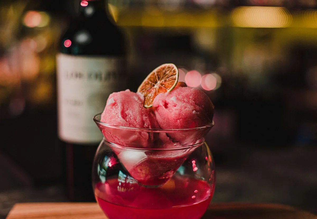 Float élégant avec boules de sorbet rose, infusion et eau gazeuse dans un verre, garni de pétales et menthe
