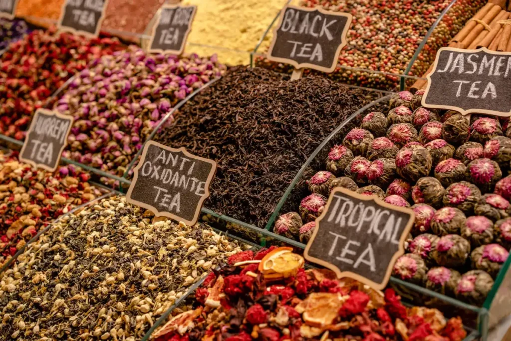 Préparation d'une tisane aux pétales de rose et épices dans une tasse, avec ingrédients naturels sur une surface en bois