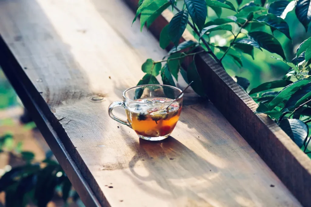Tasse de rooibos fumant avec feuilles séchées et cuillère sur surface en bois