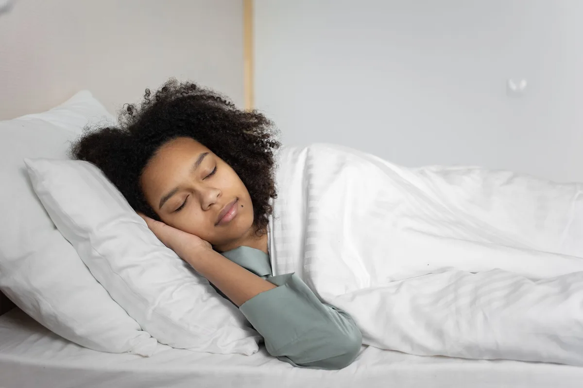 Personne dormant paisiblement dans un lit régulièrement, illustrant l'importance du sommeil pour la santé mentale