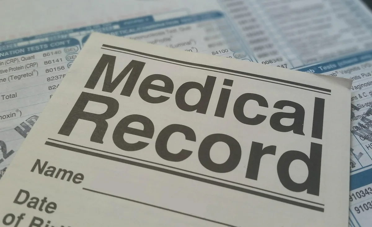 Spécialiste médical examinant un dossier patient lors d'une expertise judiciaire.