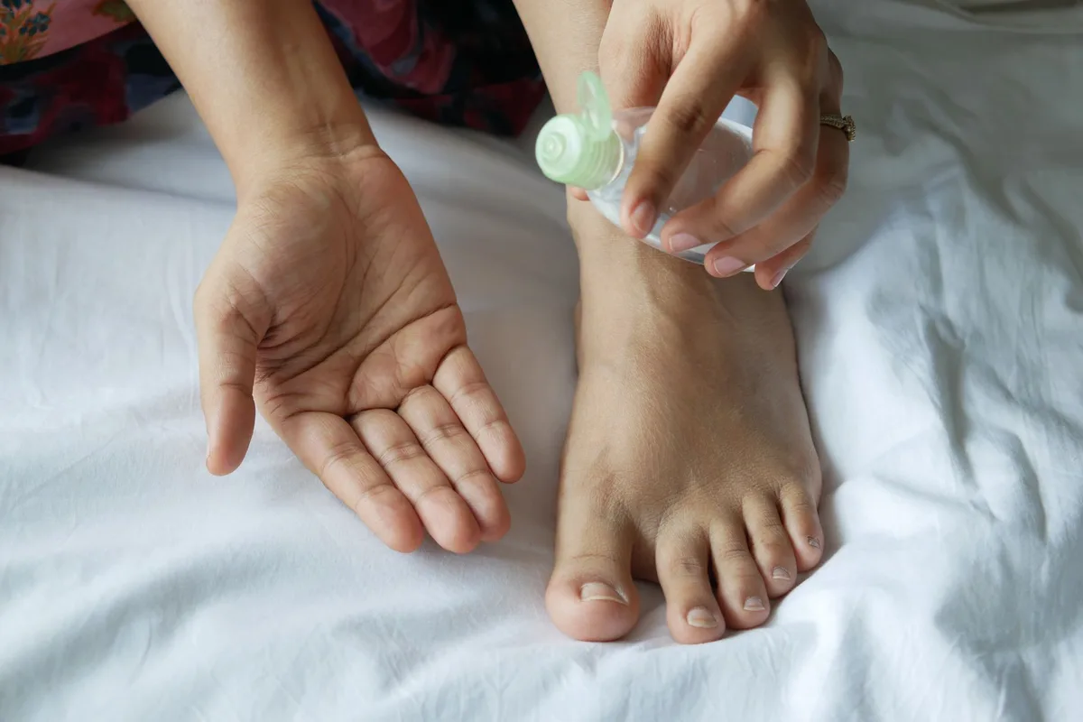 Personne appliquant une crème nourrissante sur le talon dans une salle de bain en jour