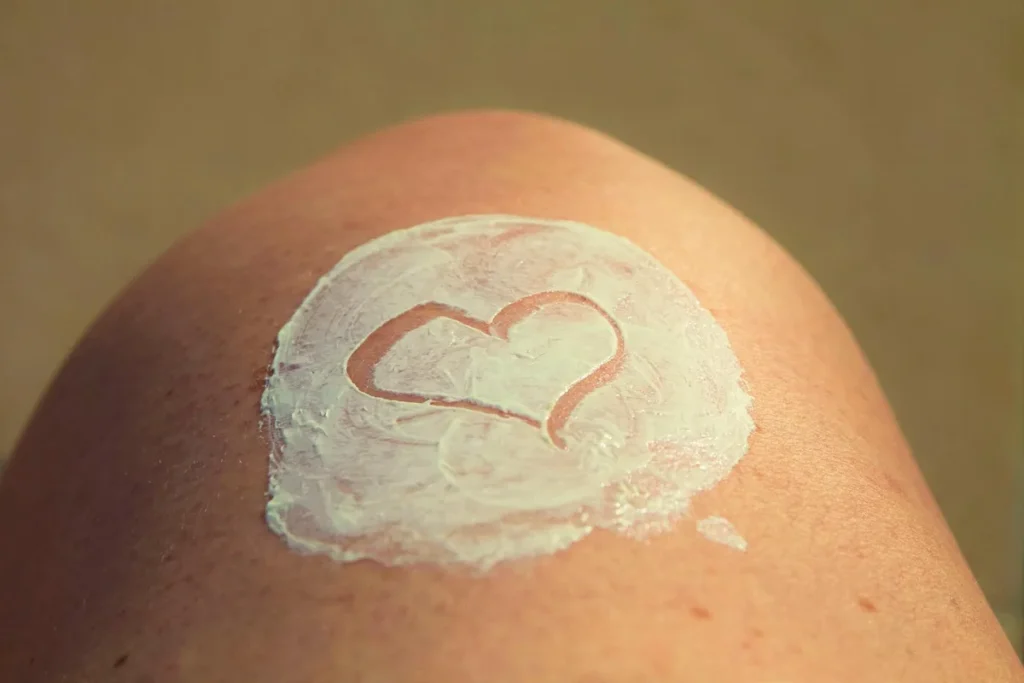Femme appliquant une crème protectrice sur son visage le matin, lumière naturelle à travers une fenêtre
