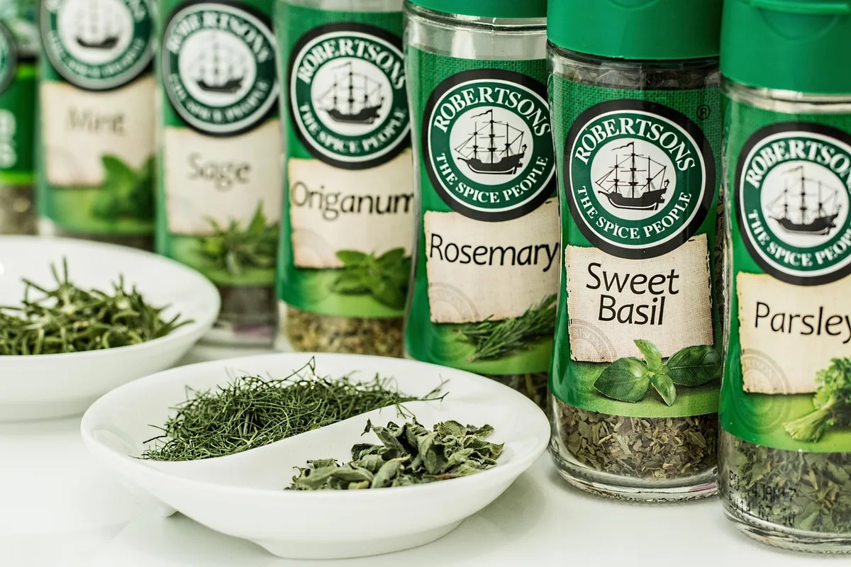 Bol de miel et vinaigre à côté d'un bocal d'herbes sur un plan de travail ensoleillé