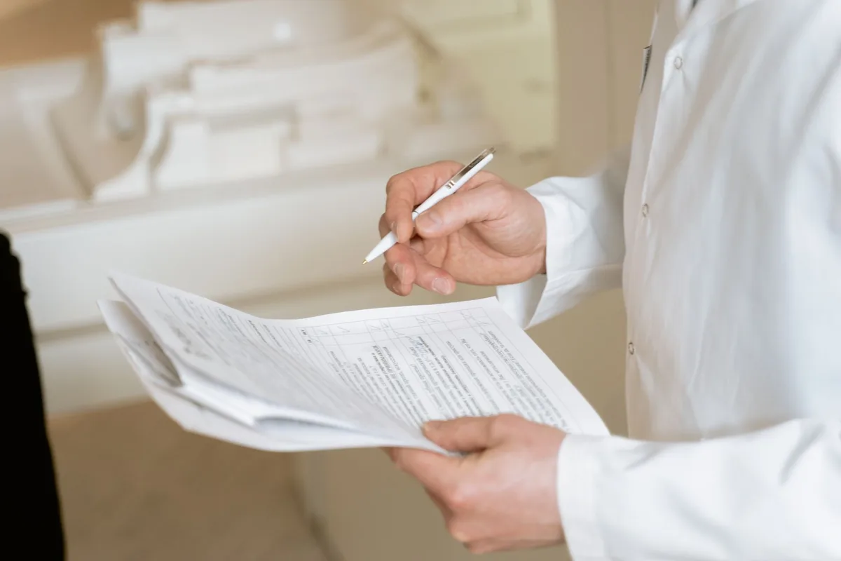 Patient discutant avec un médecin en cabinet et des documents médicaux sur la table