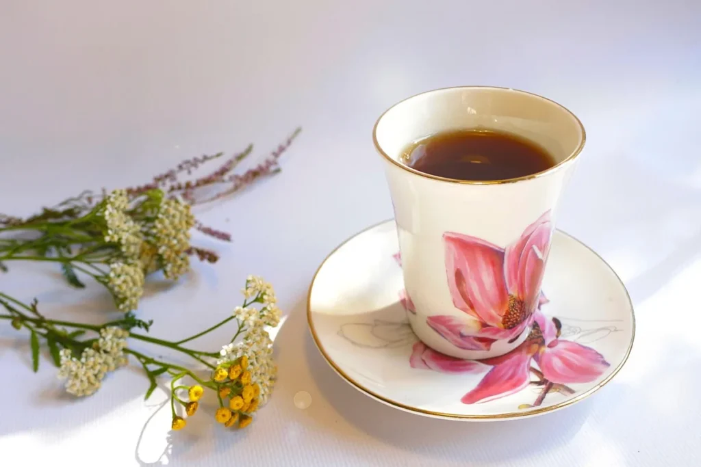 Coin de chambre en plein jour avec tasse de tisane, sachet de plantes et diffuseur flou