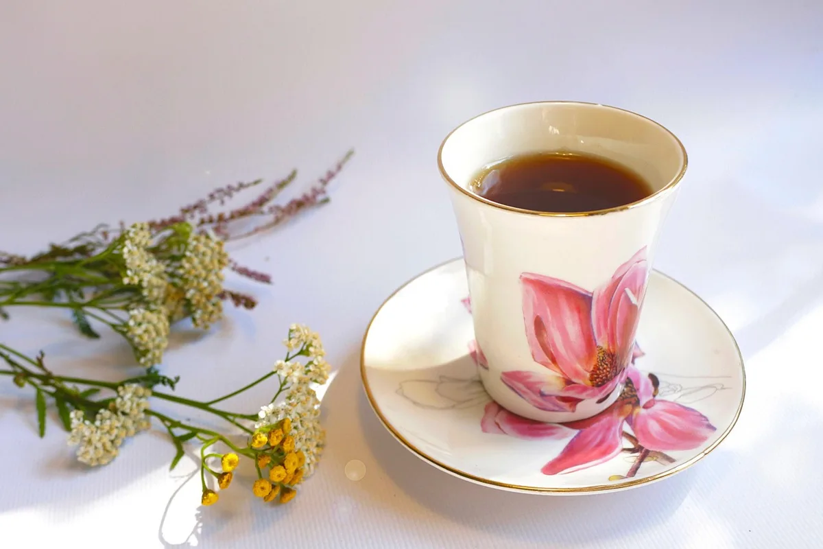 Coin de chambre en plein jour avec tasse de tisane, sachet de plantes et diffuseur flou