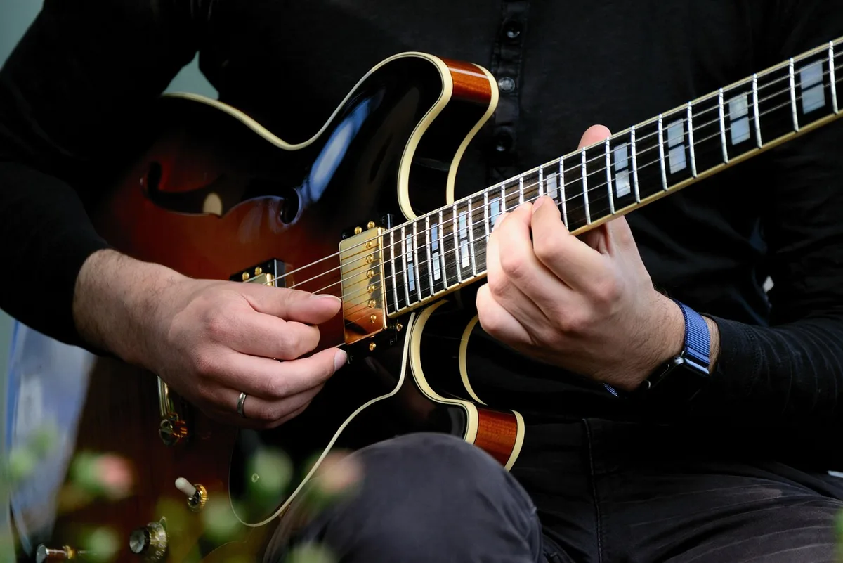 Mains posées près d'une guitare, montrant fragilité et précision réduite