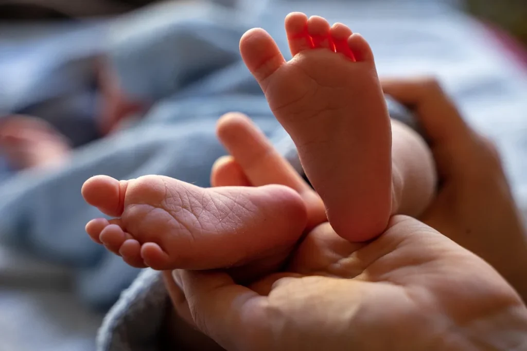 Personne anonyme appliquant une crème hydratante sur les talons dans une salle de bain lumineuse