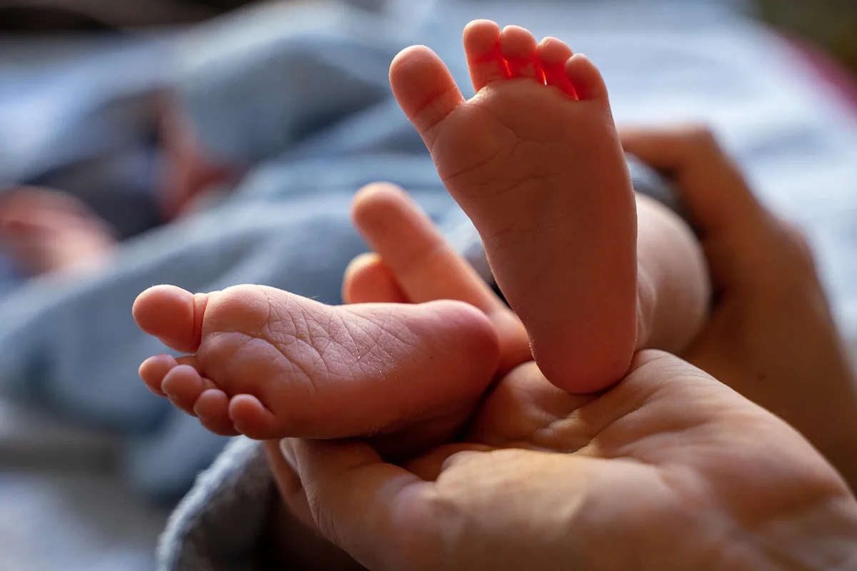 Personne anonyme appliquant une crème hydratante sur les talons dans une salle de bain lumineuse
